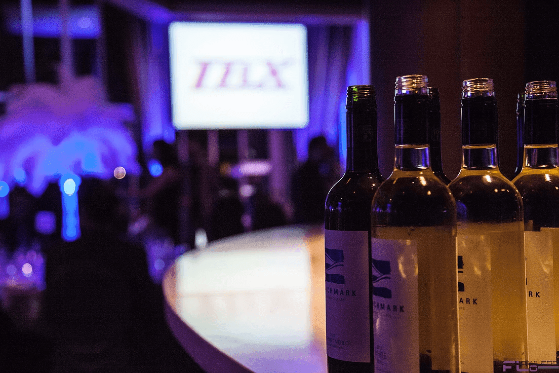 Wine bottles on the bar with the client logo projected on a screen behind