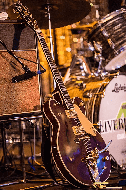 Gretsch-style hollow-body guitar leaning on a miked amp beside a Ludwig drum kit