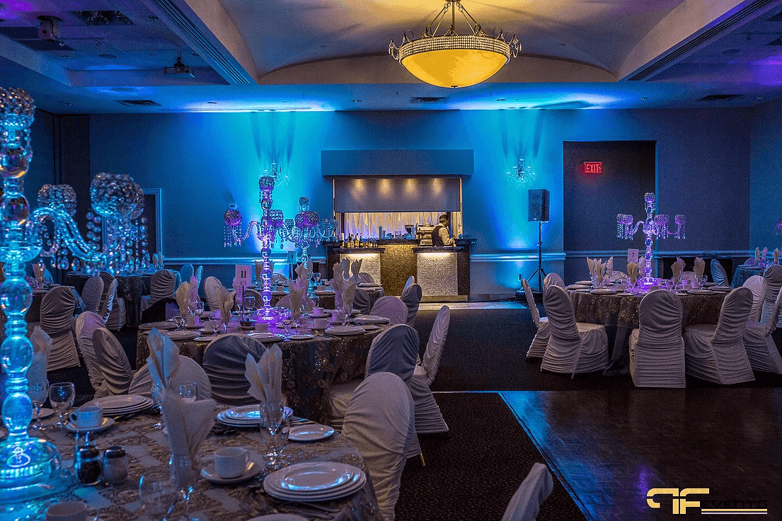 Ballroom set for dinner: crystal candelabras, blue wall uplights, parquet dance floor, PA speaker