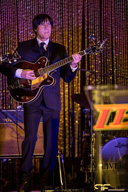 Guitarist with hollow-body guitar beside the IBX podium and Ludwig bass drum