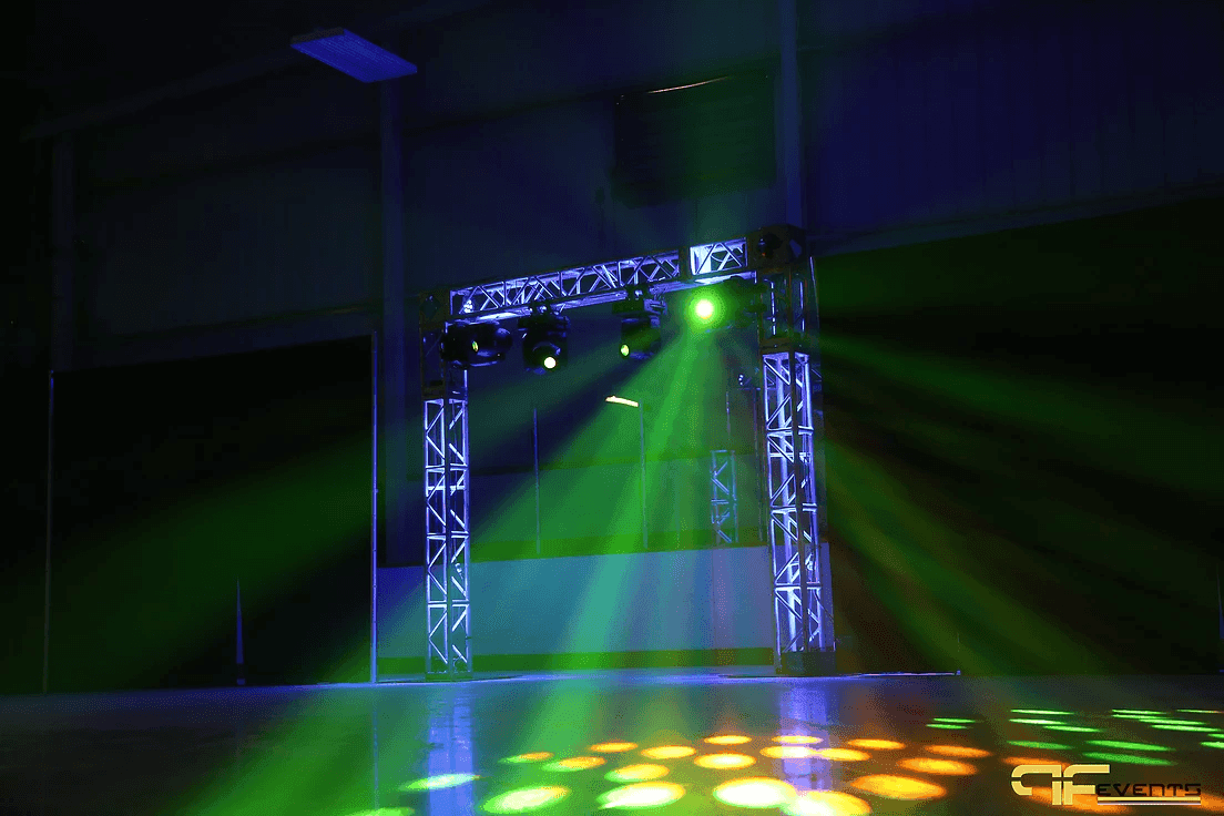 Green and amber beams from the truss arch spilling gobo patterns across the ice