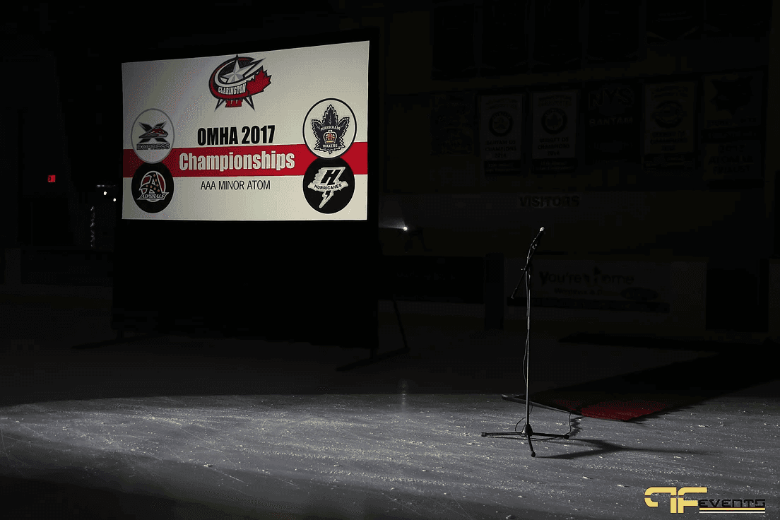 Screen on the ice reading OMHA 2017 Championships AAA Minor Atom beside a lone mic stand