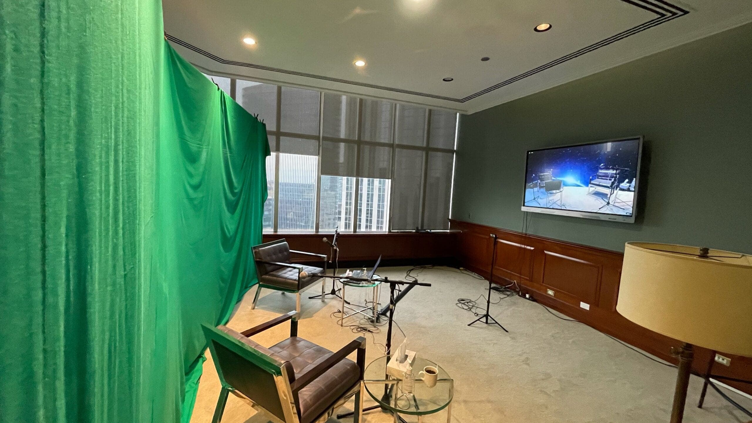 Green-screen interview set with two chairs and mics in a boardroom