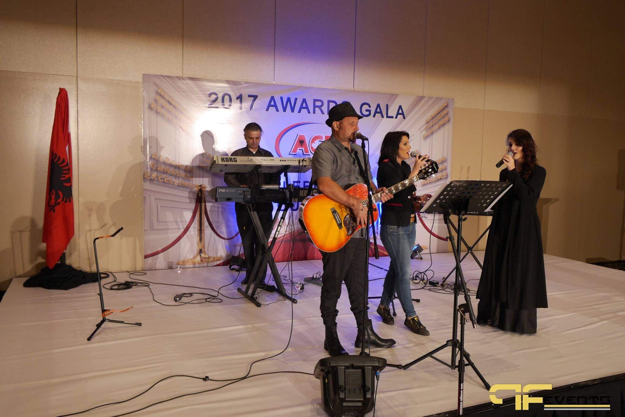 Band with acoustic guitar and three vocalists on the ACE gala stage