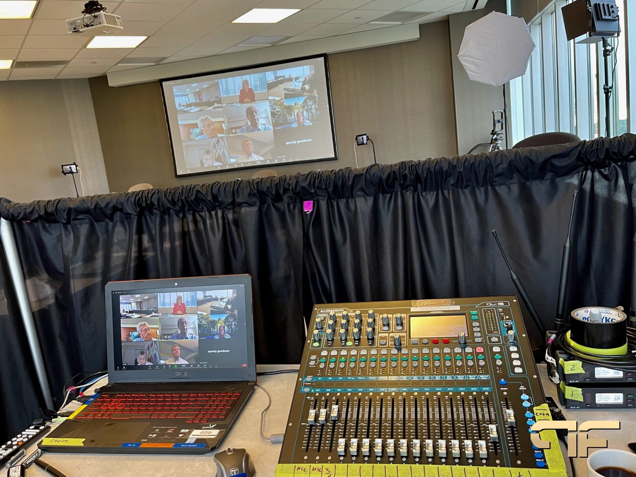 Digital mixer and Zoom laptop at a hybrid meeting with a projected gallery