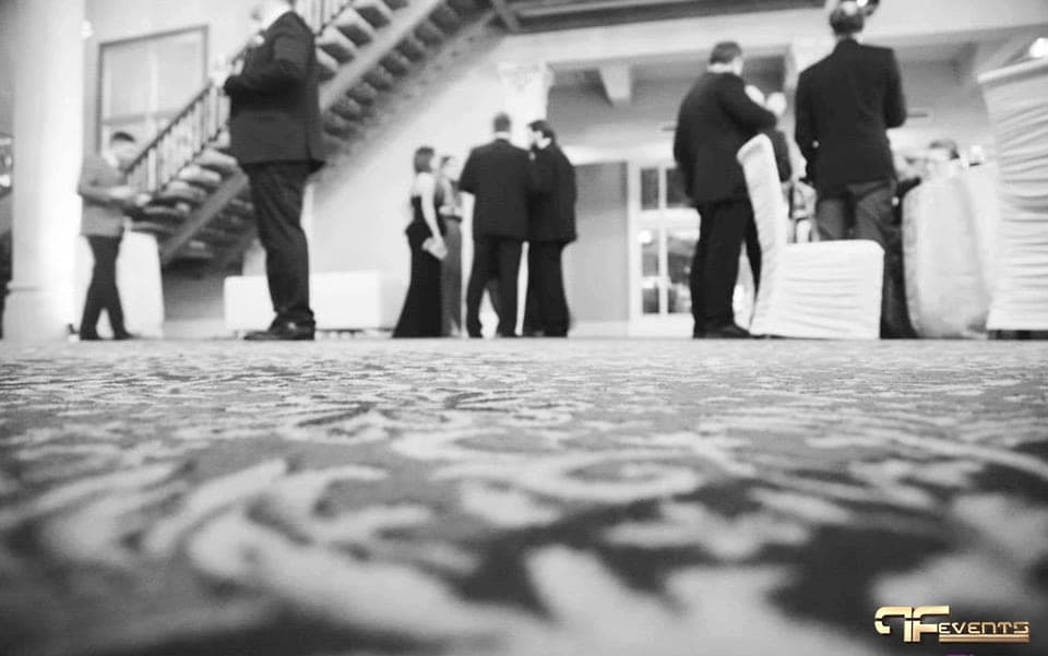 Black-tie guests mingling by white-covered chairs, black and white photo