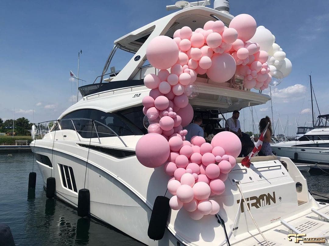 Pink and white balloon garland décor on a yacht docked at a marina