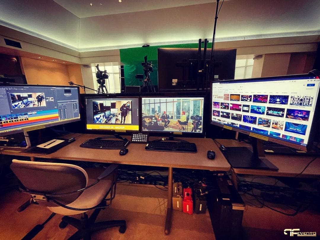 Webcast control desk with encoder screens, green screen and cameras behind