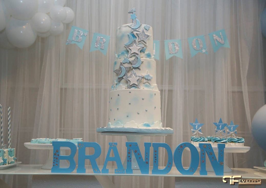 Three-tier star and moon cake under name bunting on a sheer white backdrop
