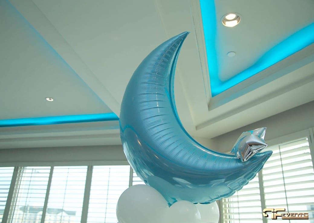 Pale blue crescent-moon balloon under turquoise cove lighting in an Oakville banquet room