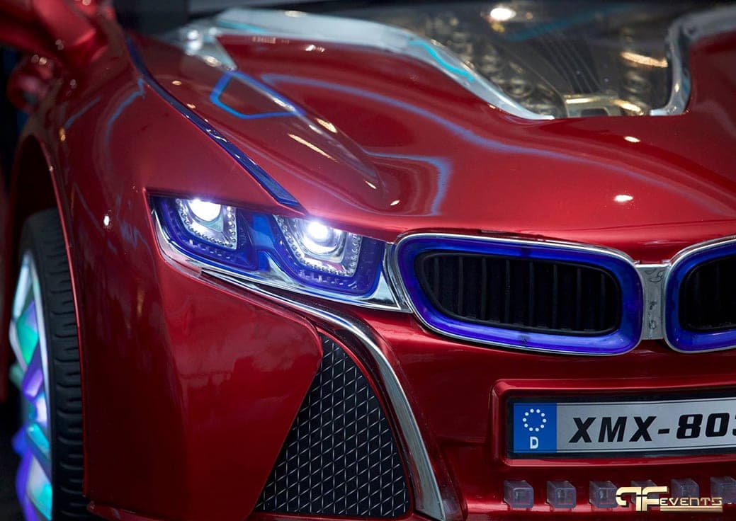 LED headlights on a red children's ride-on car at a first-birthday party