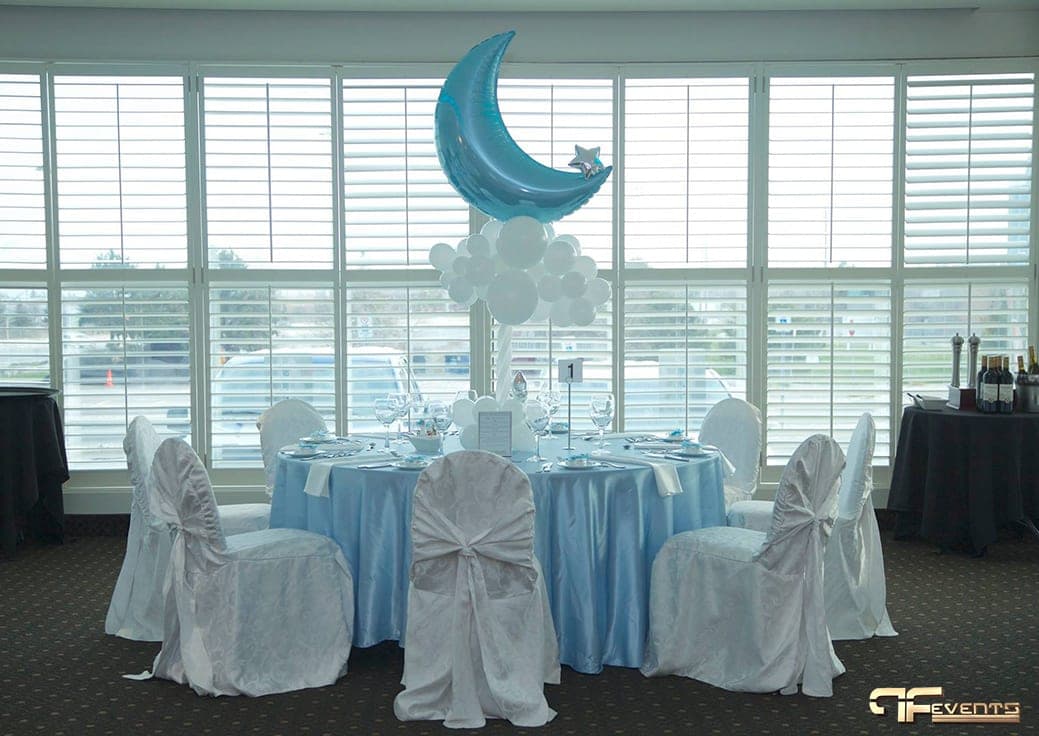 Round table in baby blue and white with a moon and cloud balloon centrepiece