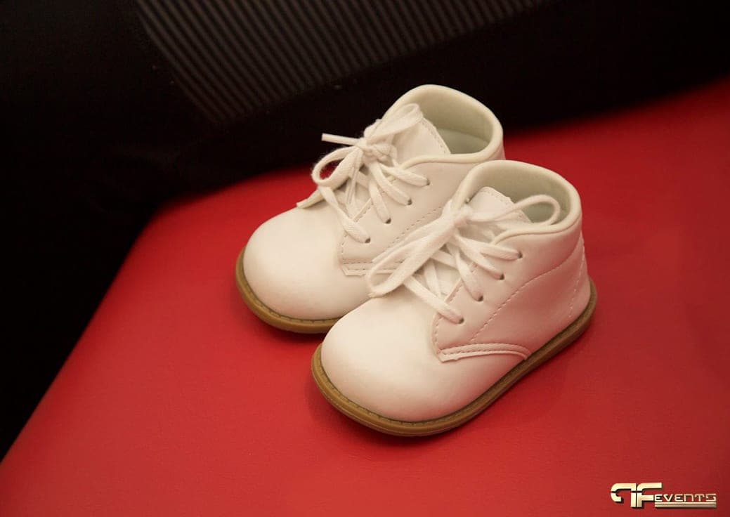 Pair of white baby shoes on a red seat
