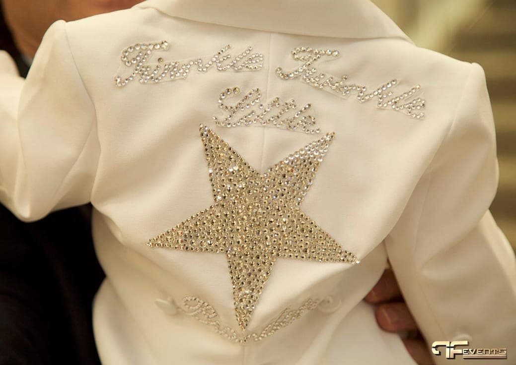 Rhinestone star and script lettering on the back of a white baby jacket