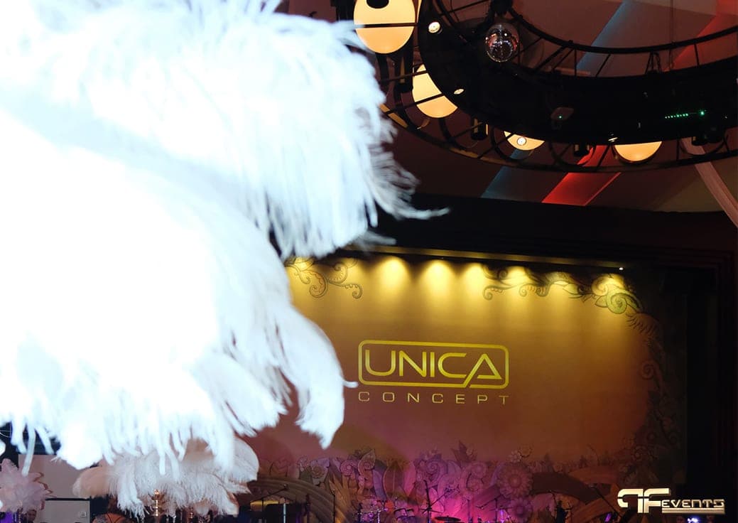White feather centrepiece with Unica Concept projected on the stage wall
