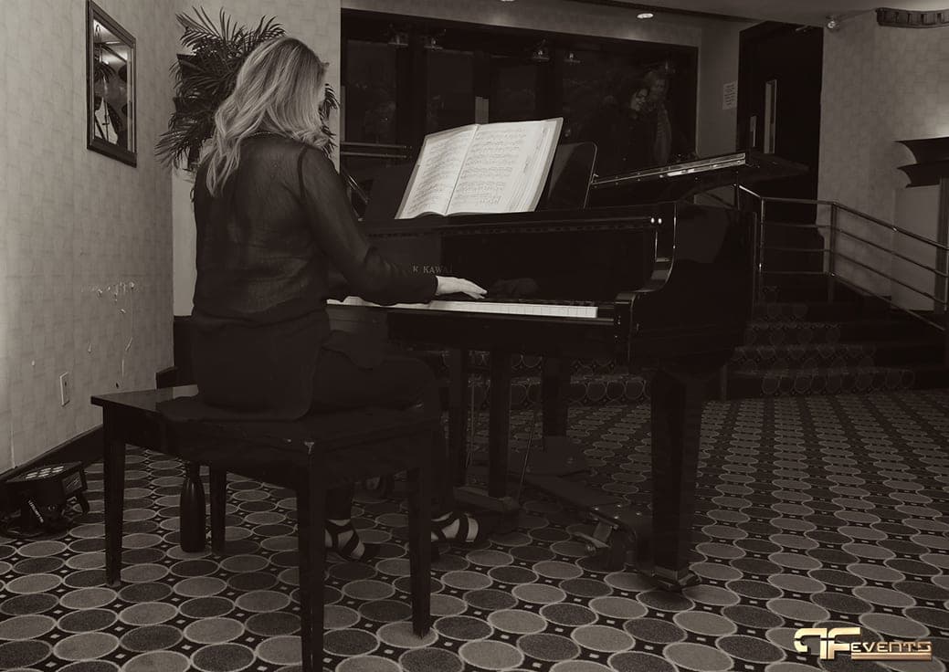 Pianist at a grand piano in the Eglinton Grand foyer, black and white