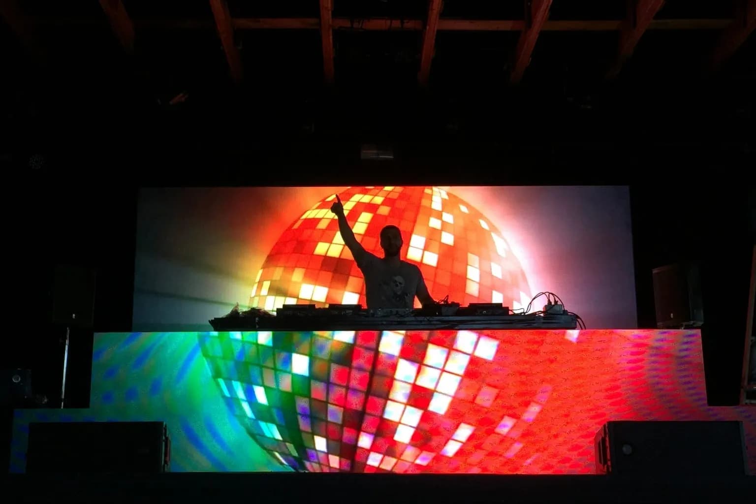DJ performing in front of a disco-ball LED backdrop at a corporate holiday party
