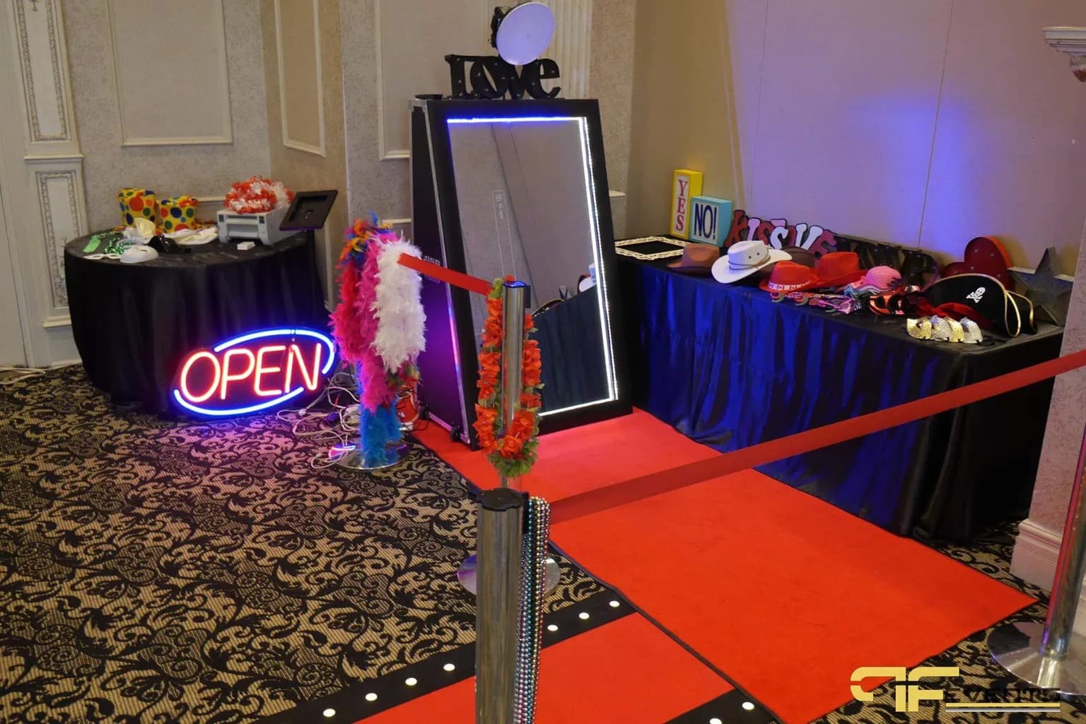 Photo booth with a neon sign, props, and a red carpet at a corporate holiday party