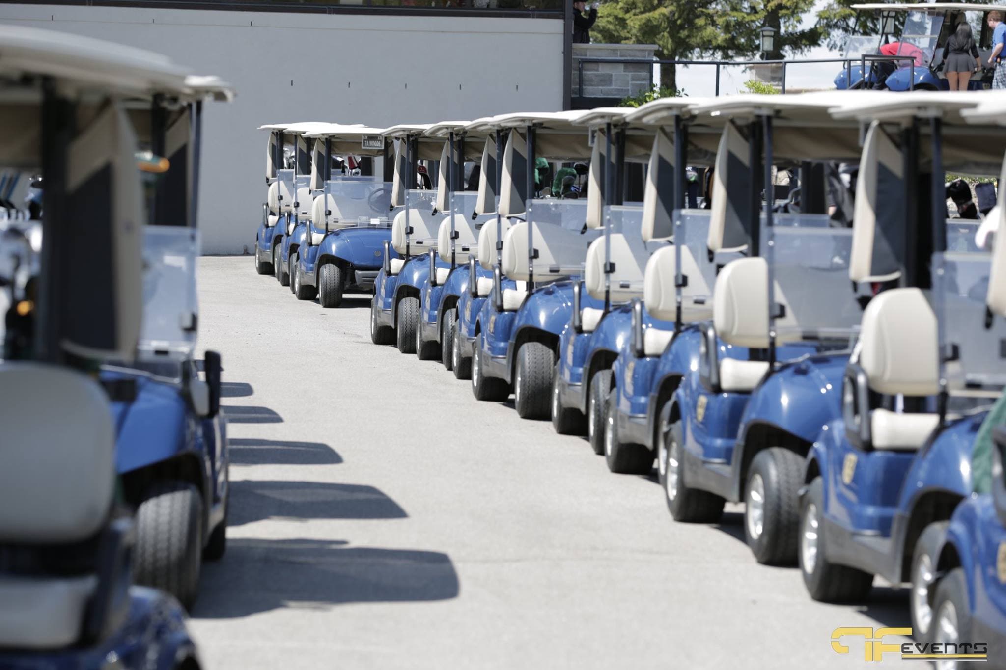 Blue golf carts lined up outside the clubhouse before the shotgun start