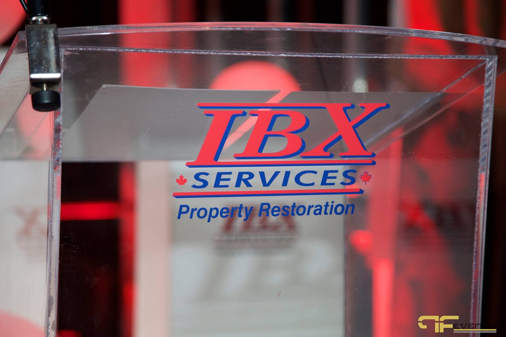 Clear acrylic podium printed with IBX Services Property Restoration logo