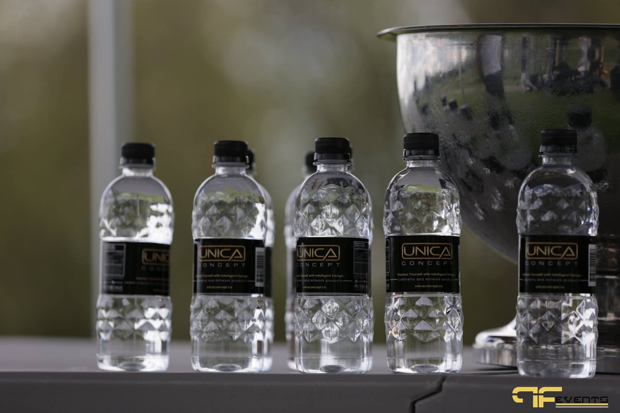 Sponsor-branded water bottles beside a steel ice bowl