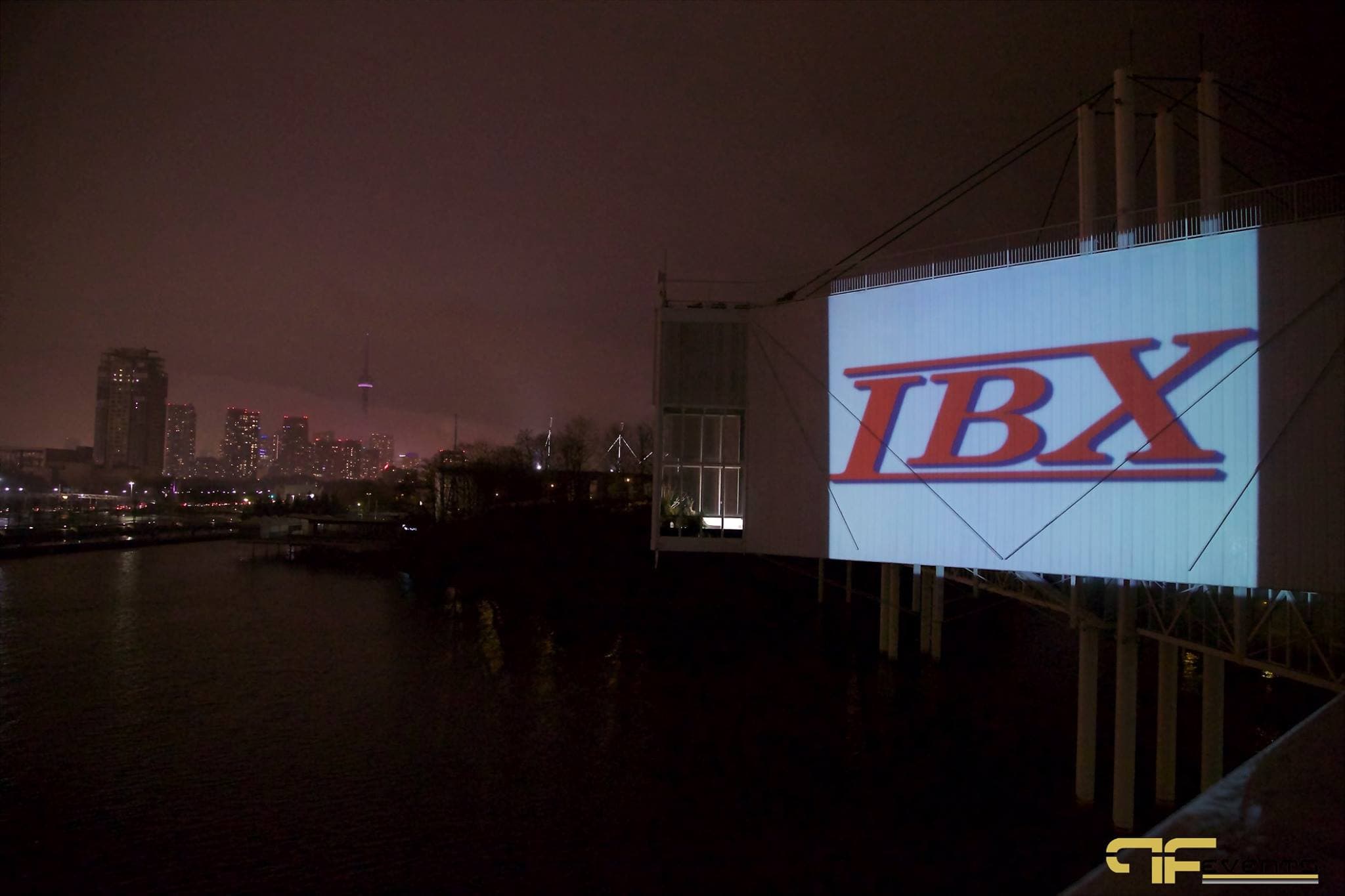 IBX logo projected onto the Atlantis building exterior over water, CN Tower in distance