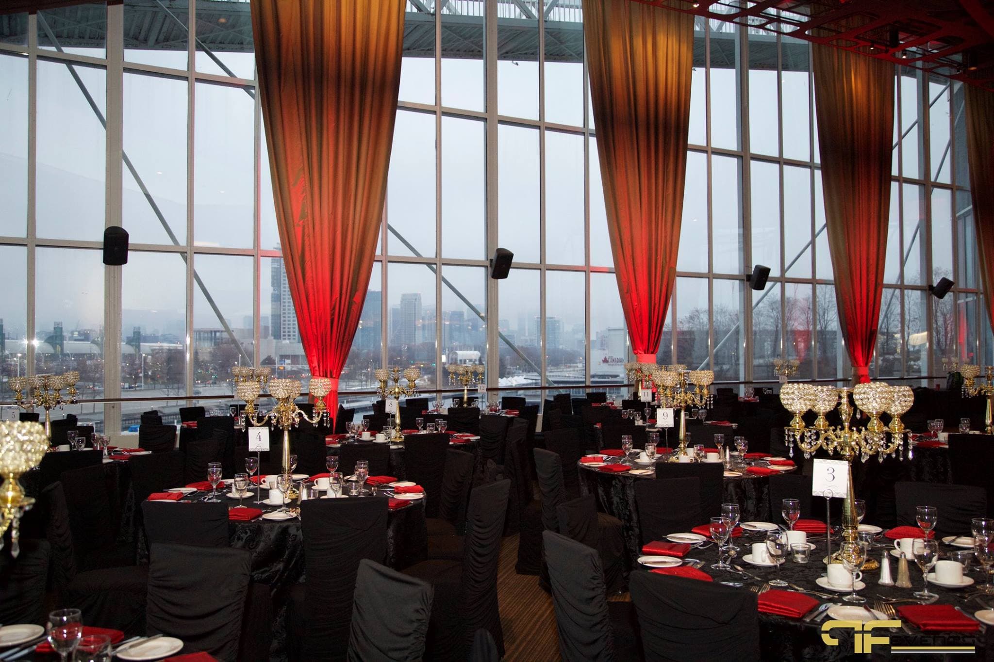 Atlantis glass pavilion set for dinner, red-uplit drapes, gold candelabras, skyline beyond