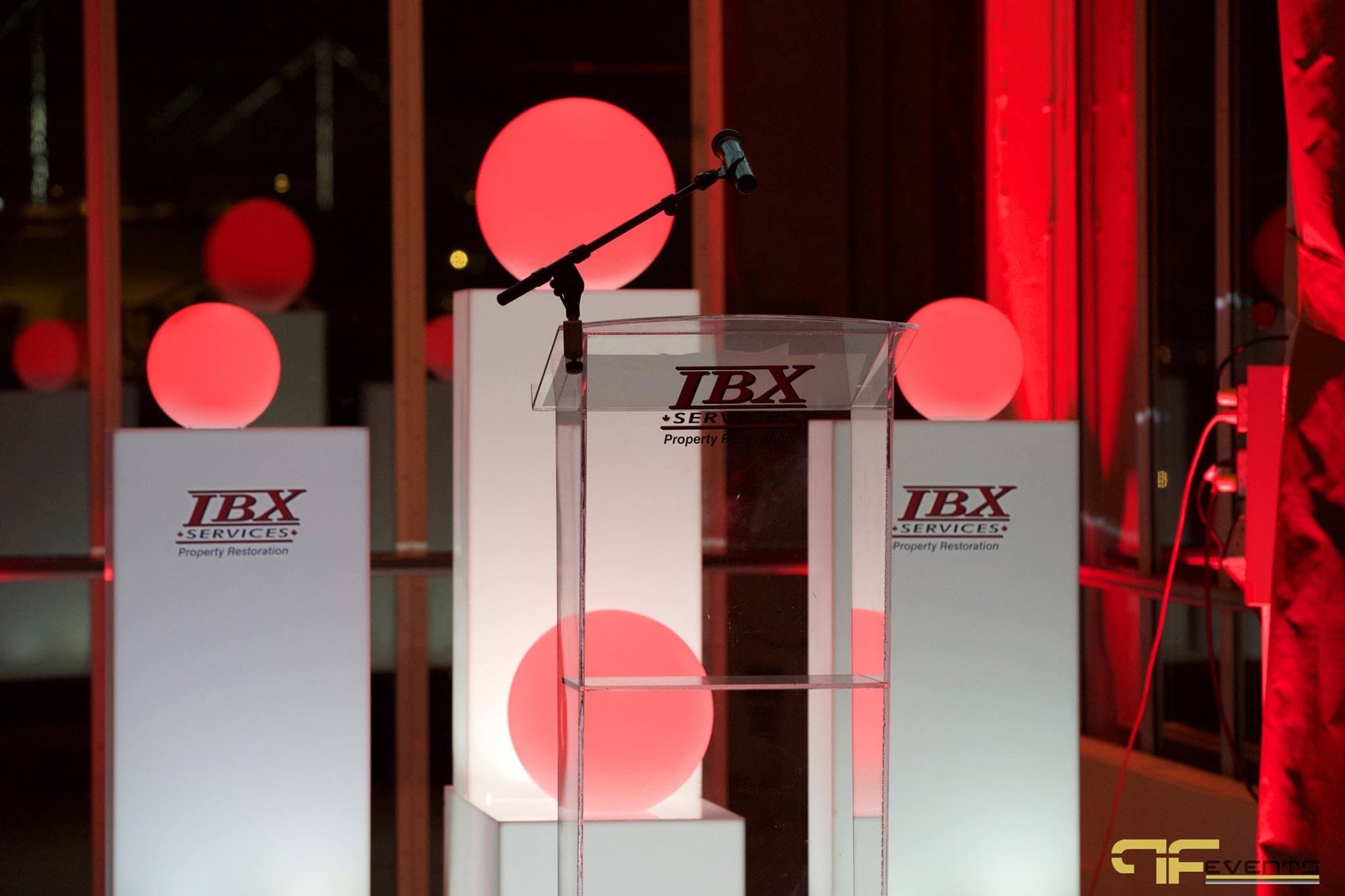 Acrylic lectern with boom mic between IBX-branded plinths and glowing red spheres