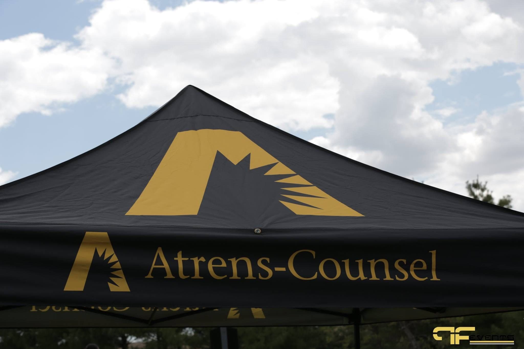 Black sponsor pop-up tent printed with a gold logo against the sky