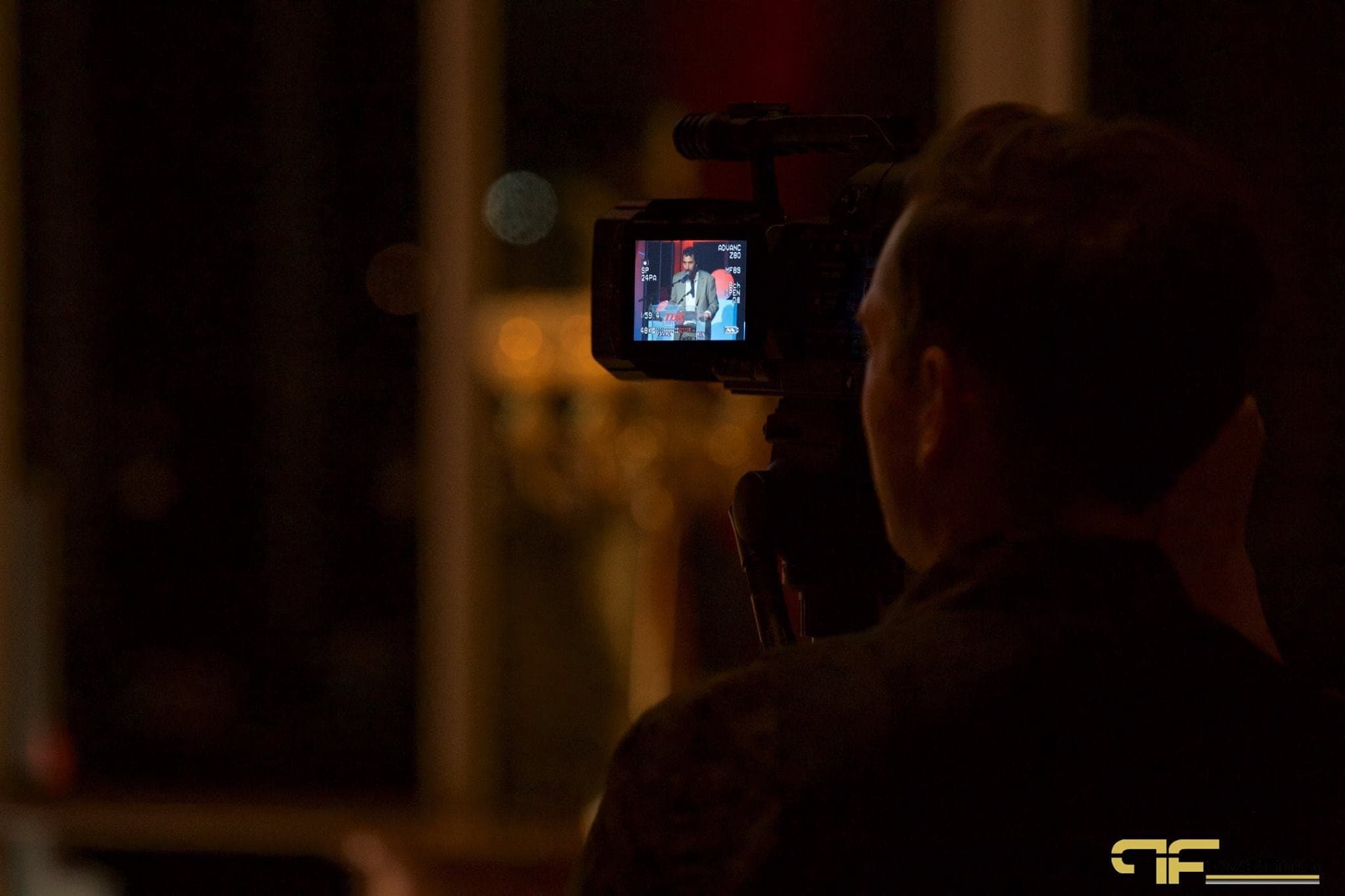Videographer's camera monitor framing the speaker at the podium