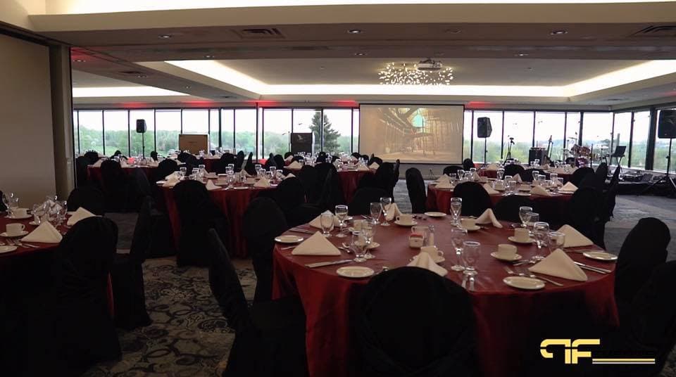 Clubhouse dinner room with red linens, projection screen and speakers on stands