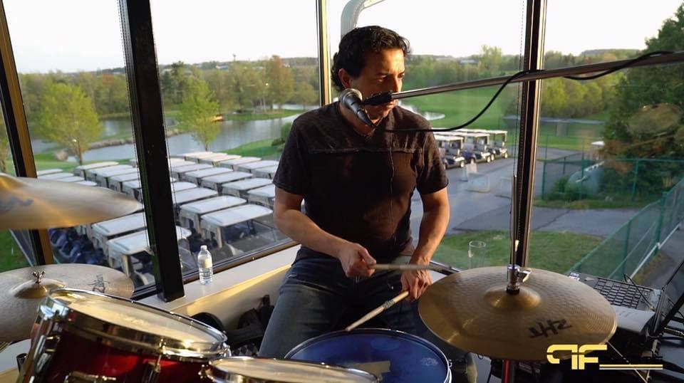 Drummer playing by a window overlooking the cart park and pond