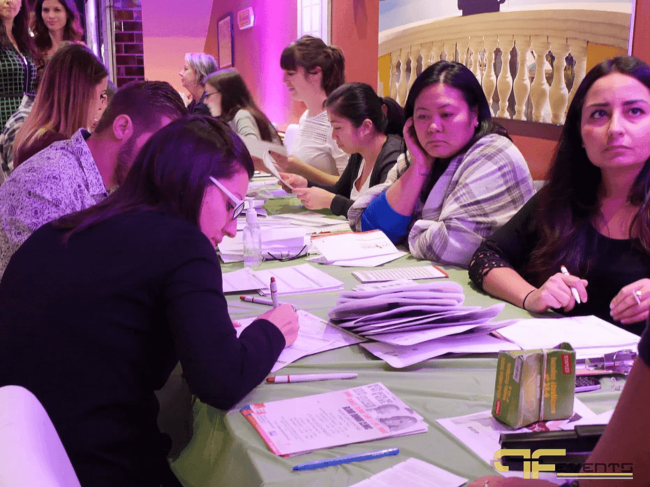 Guests completing donor health questionnaires at long green tables