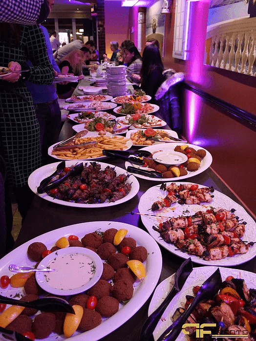 Buffet of kebabs, falafel and appetisers under purple uplighting