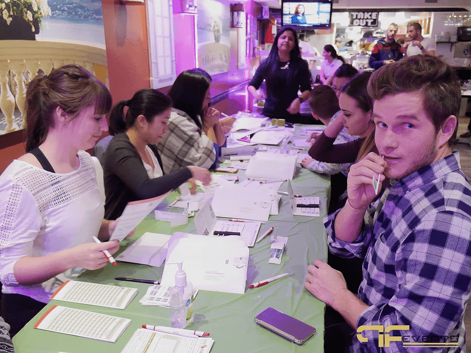 Row of registrants at green tables, one mid cheek swab