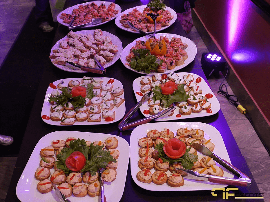 Platters of crostini beside a floor LED uplight casting purple