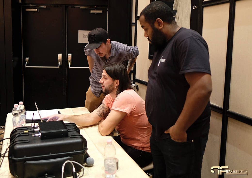 Crew checking a wireless mic system and laptop at a side table before the IBX gala