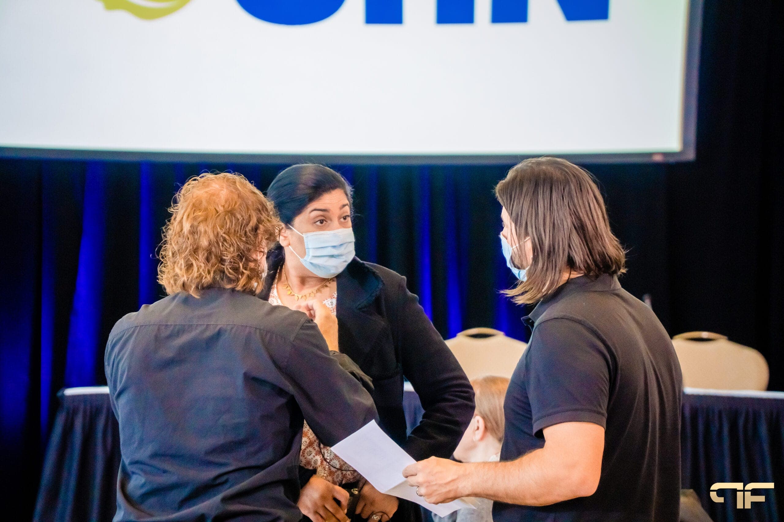 Crew confer with an organizer before the UHN head table and screen