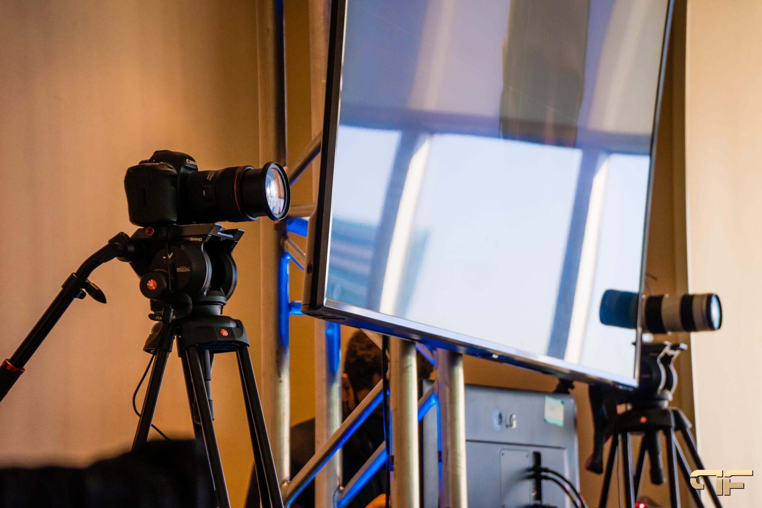 DSLR and cinema camera on tripods flanking a monitor mounted on truss