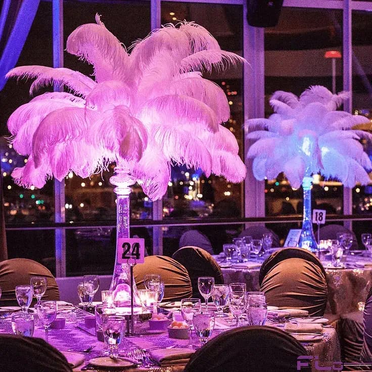 A beautifully decorated banquet table with illuminated feather centerpieces