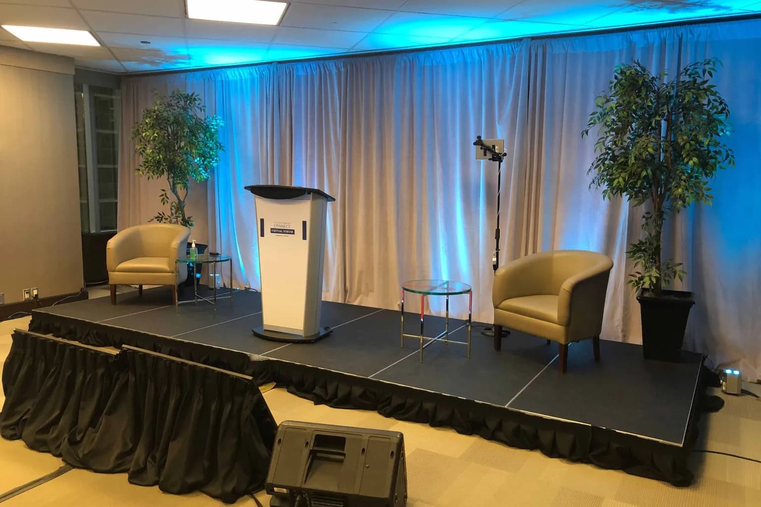Stage with lectern, lounge chairs and uplighting set for a corporate presentation