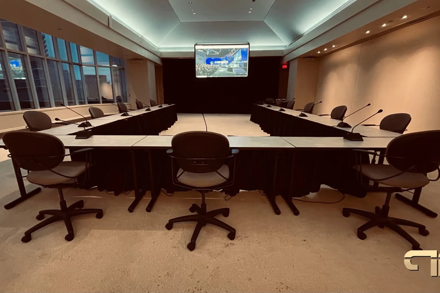 Breakout room set in a U-shape with table microphones at every seat and a display screen at the far end