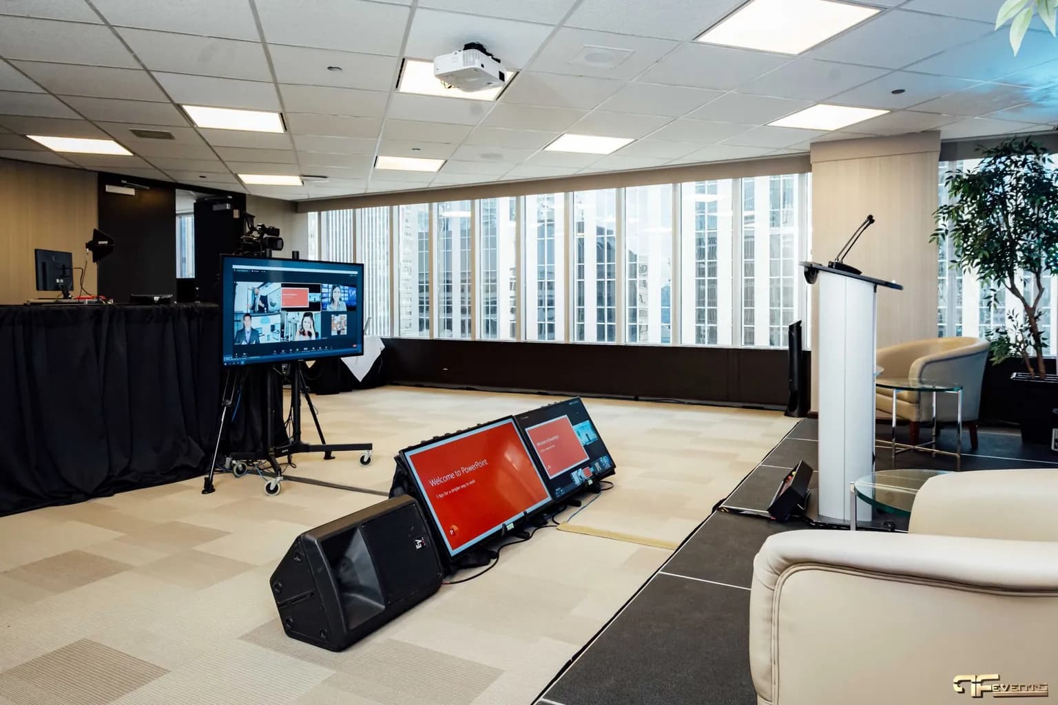 Corporate stage with a lectern, floor confidence monitors showing the presenter's slides, and a display for remote speakers